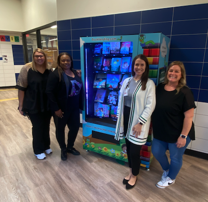 The principal, assistant principals, and librarian standing in front of a book vending machine